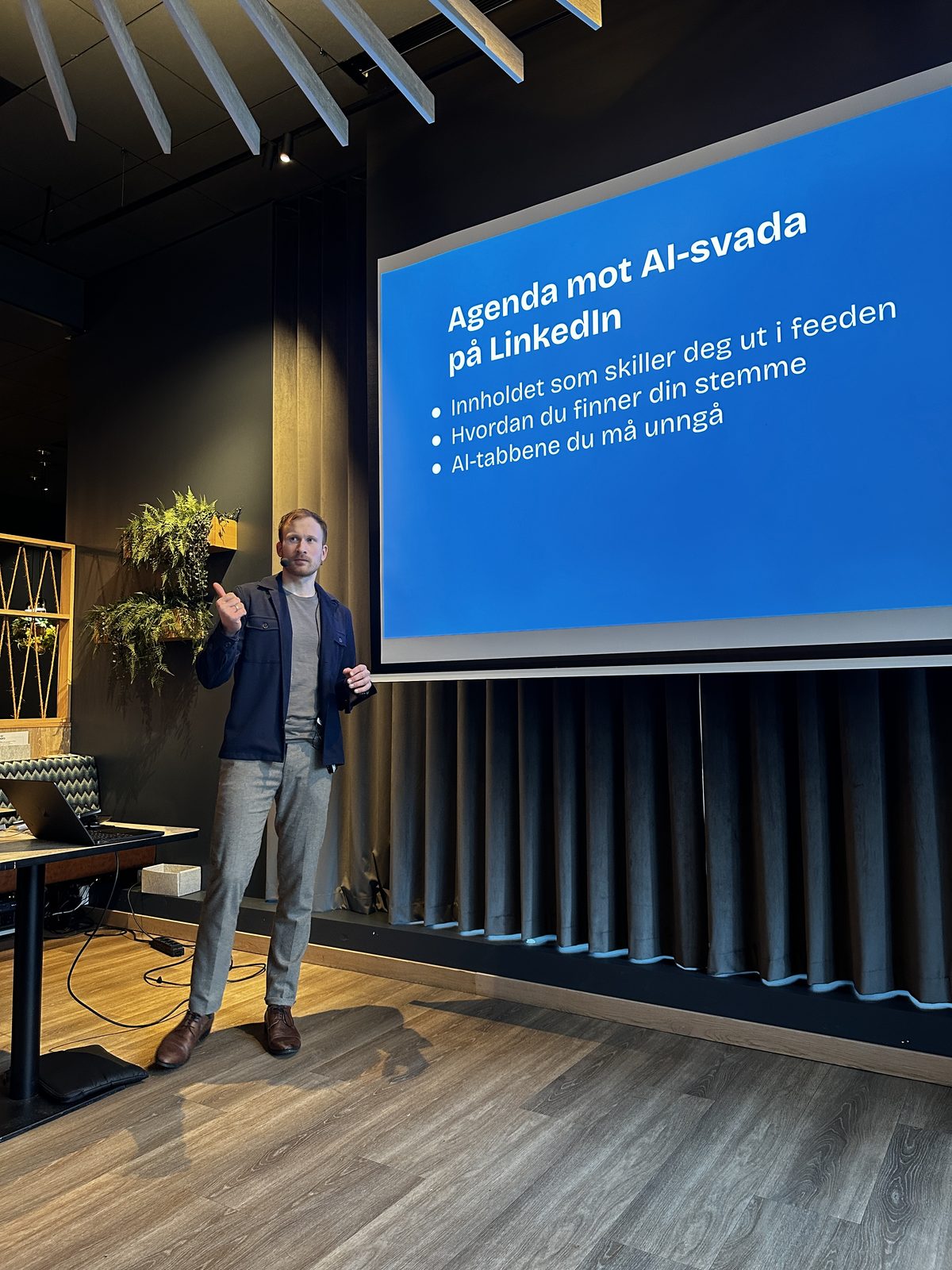 Erlend Haddeland på scenen foran lysbildet «Agenda mot AI-svada på LinkedIn»